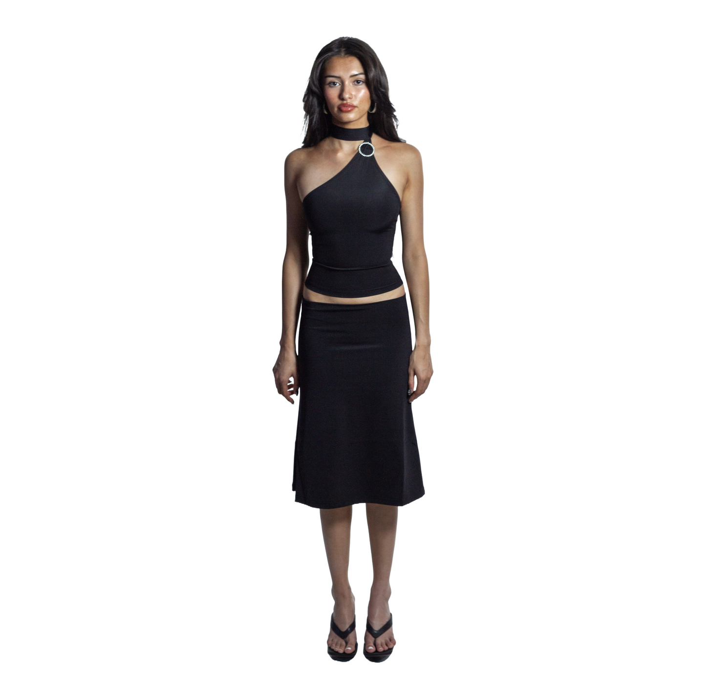 Full body front view of jet black self-tieing asymetrical top with circle brooch and midi knee-length skirt